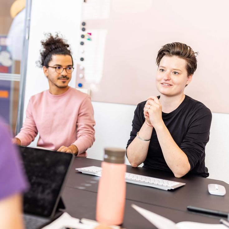Zwei Frauen und ein Mann besprechen sich in einem Meeting
