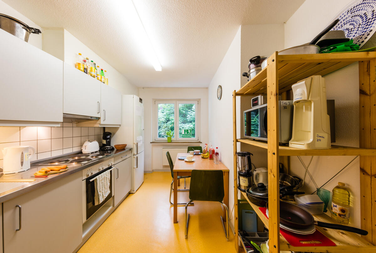 Küche mit Tisch, Stühlen und Regal im Wohnheim in der Landhausstraße